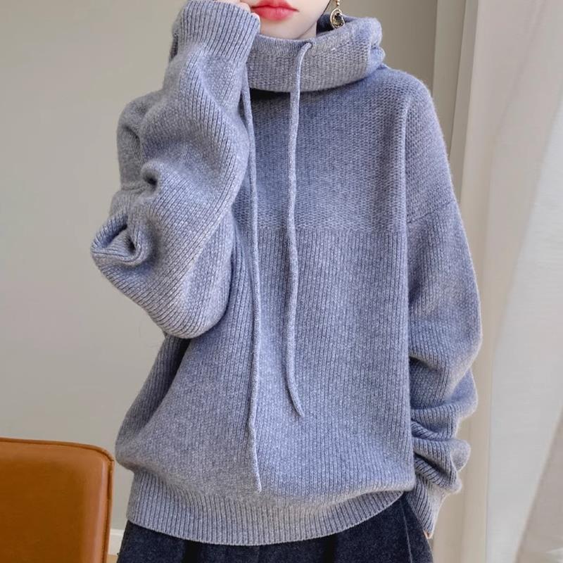 Person wearing a blue knitted hoodie with a neutral background