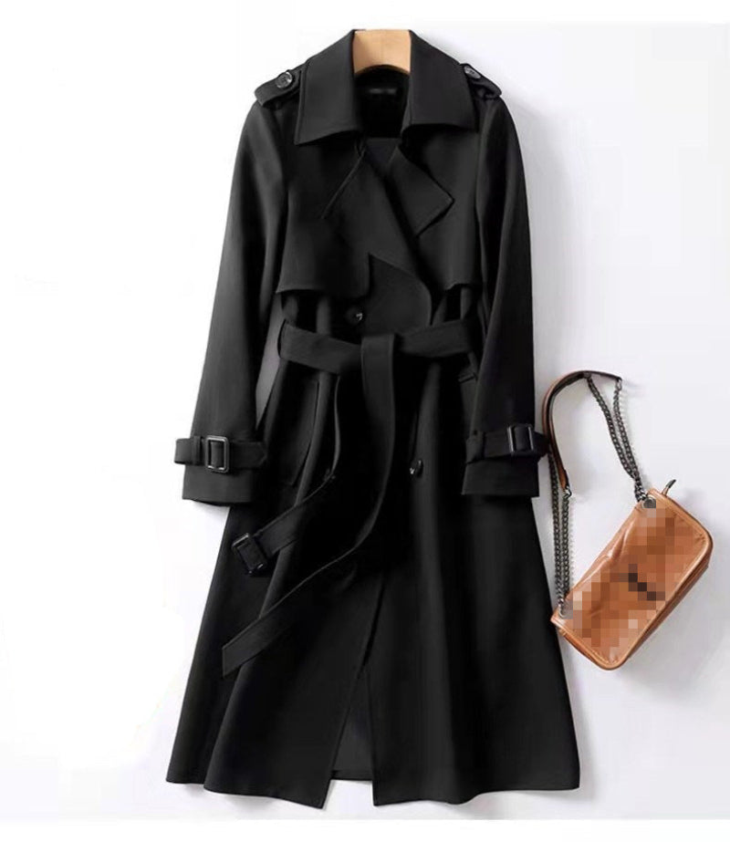 Black trench coat with a wooden hanger and brown handbag on a white background