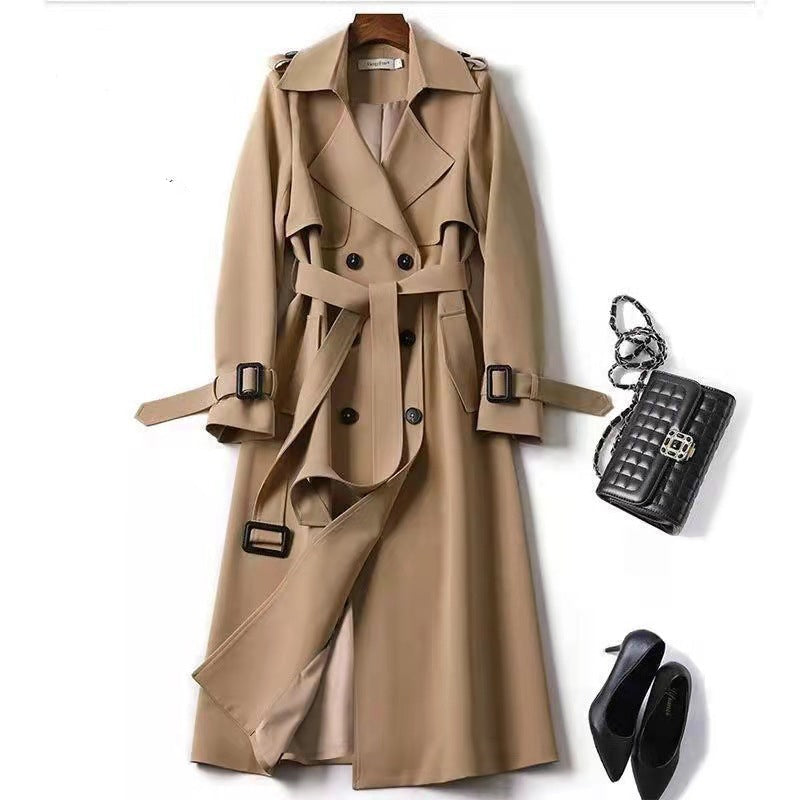 Beige trench coat with black handbag and shoes on a white background
