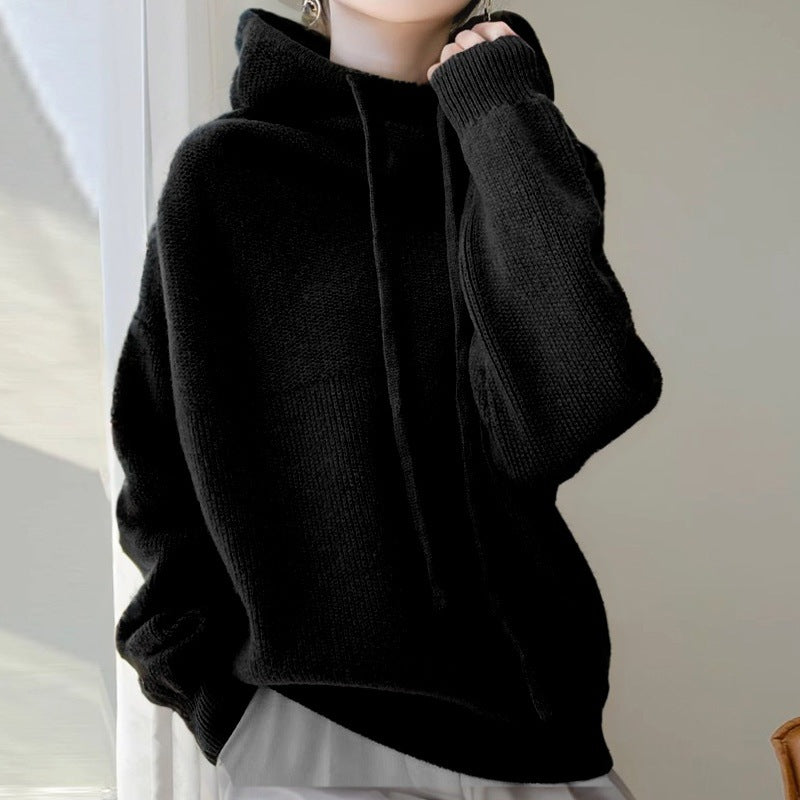 Person wearing a black sweater against a neutral background