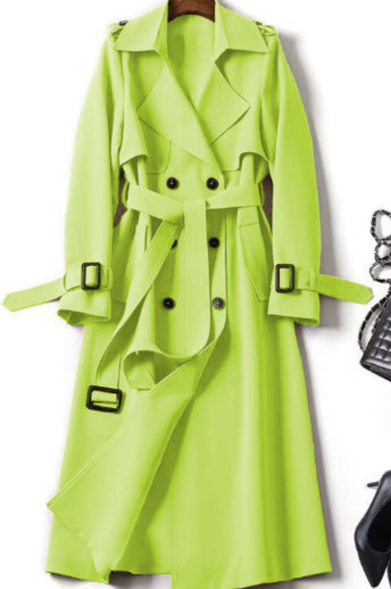 Green trench coat on a hanger with a black handbag and shoes in the background