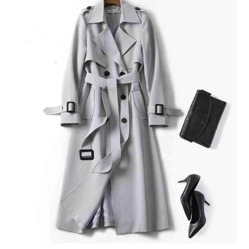 Gray trench coat with black clutch and high heels on a white background