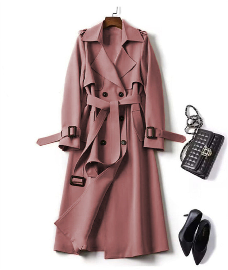 Pink trench coat with black handbag and shoes on a white background