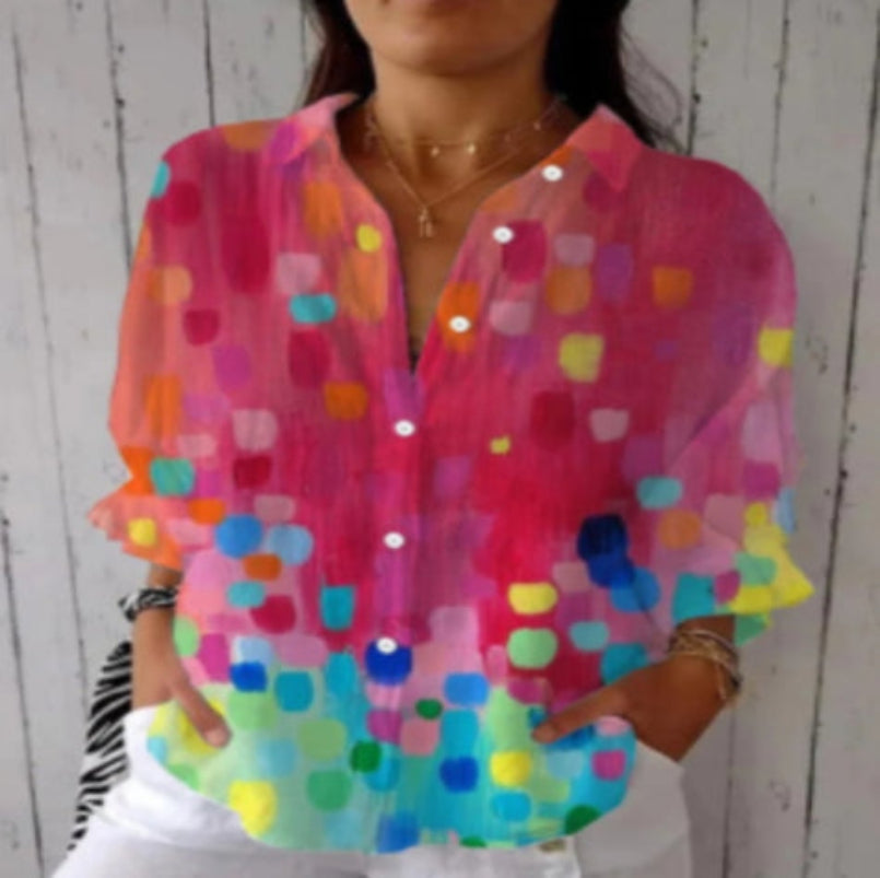 Person wearing a colorful, patterned blouse against a white wooden panel background