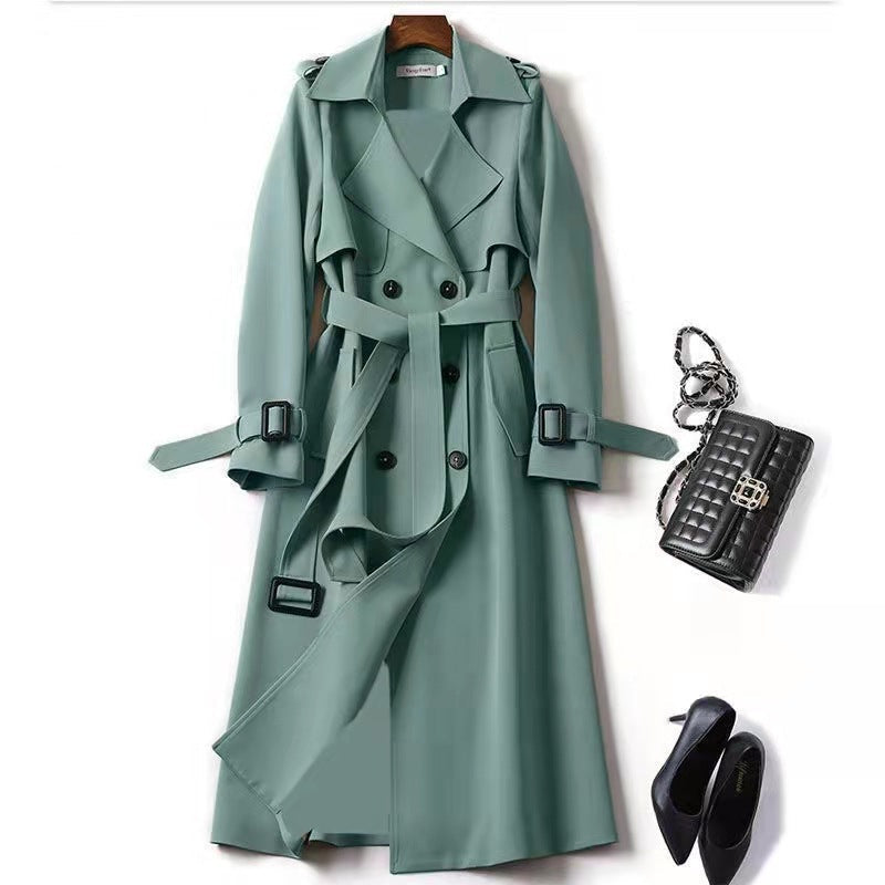 Green trench coat with black accessories on a white background